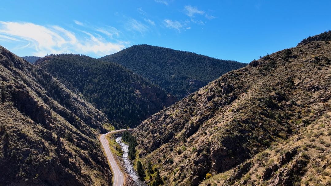 Aerial drone photo in the Colorado mountains of beautiful skies and winding highway. Clear view of distant hills colorful sky near Black Hawk Best Motorcycle Roads in Colorado