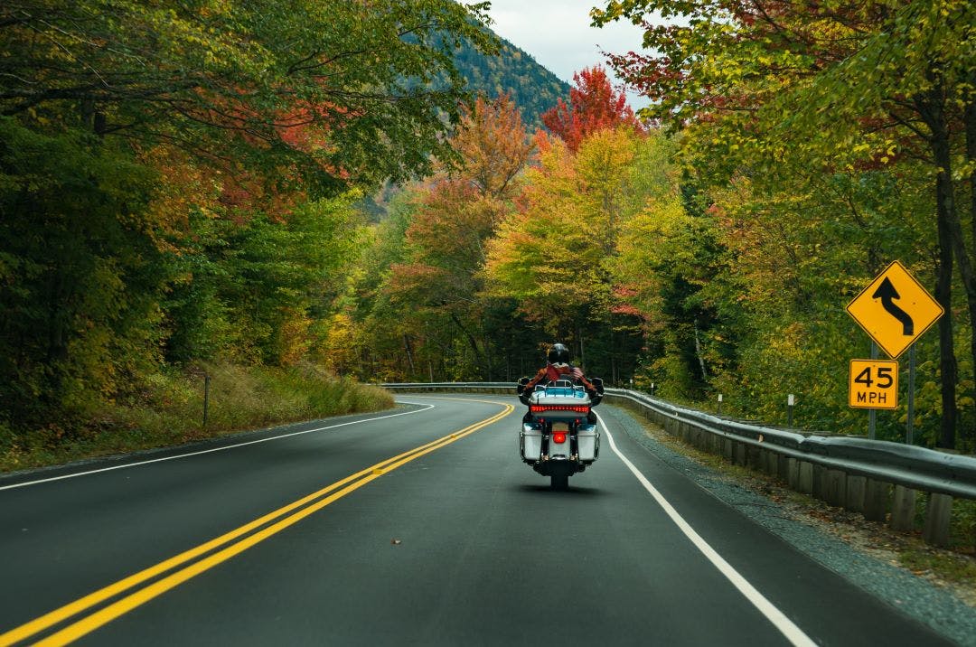 picture of harley davidson motorcycle and rider driving through mountain roads in fall Tips for Touring on a Harley-Davidson