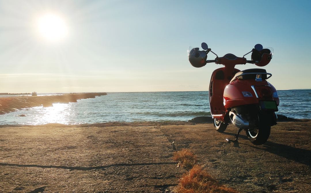 red vespa at the seashore Can Vespas Go On the Highway? Vespa Riding FAQs