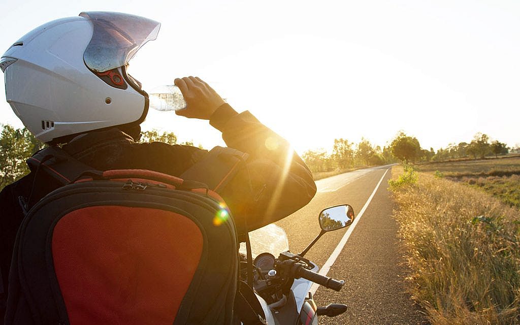 motorcycle rider taking break drinking water riding in heat how hot is too hot for motorcycle riding tips and tricks