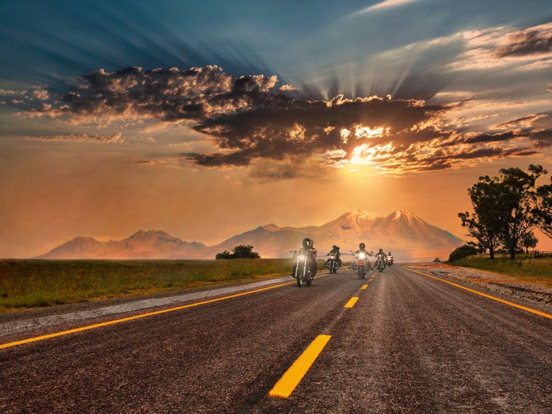 group of motorcycle riders on a road at sunset Motorcycle Hand Signals You Should Know