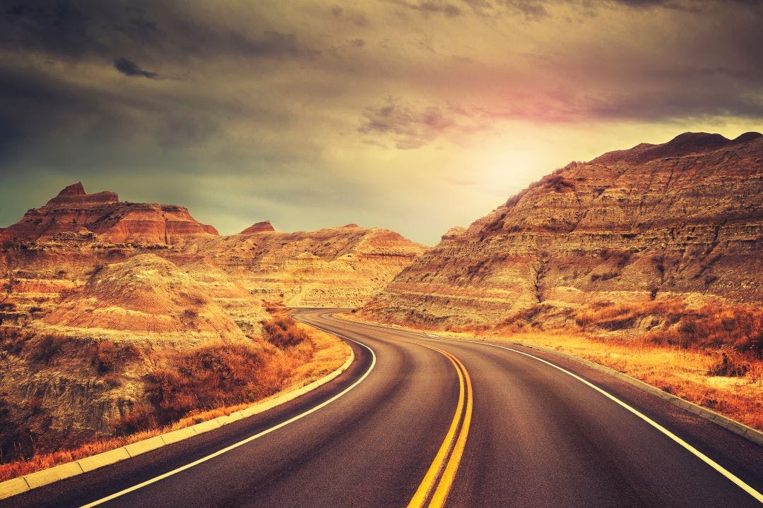 Scenic road at sunset, color toned picture, Badlands National Park, South Dakota, USA. The Ultimate Badlands National Park Motorcycle Ride