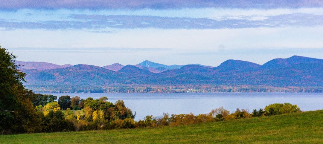 view of Lake Champlain and the Adirondack Mountains in New York from Shelburne Farms in Vermont Top 8 Best Motorcycle Rides in New York State