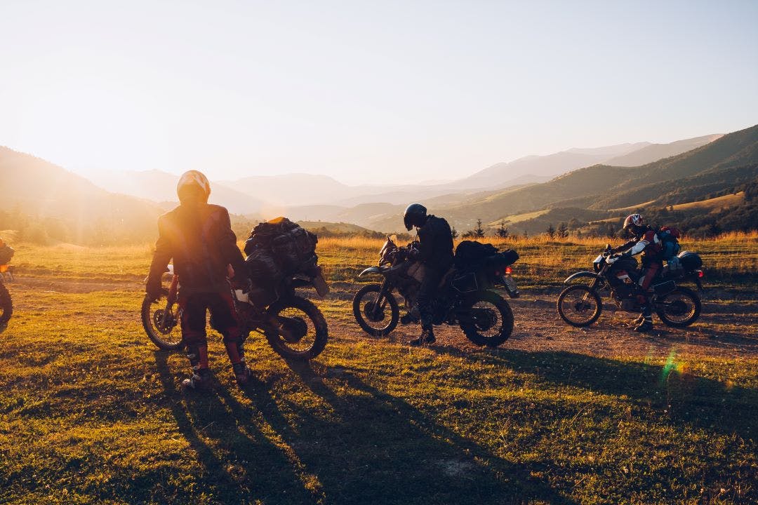 group of motorcycle riders on adventure and dual sport motorcycles at sunset Dual Sport vs. Adventure Bikes - Let's Break It Down