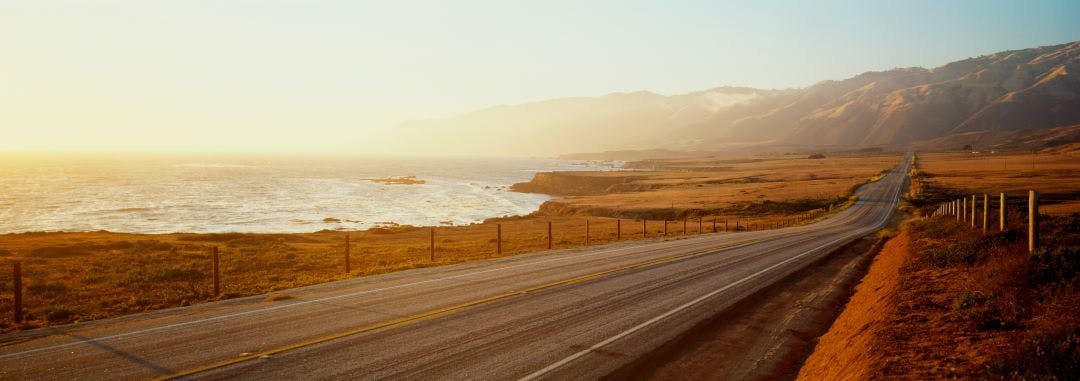 This is Route 1also known as the Pacific Coast Highway. The road is situated next to the ocean with the mountains in the distance. The road goes off into infinity into the sunset. Best Motorcycle Rides in Northern California - Bay Area to the Redwoods