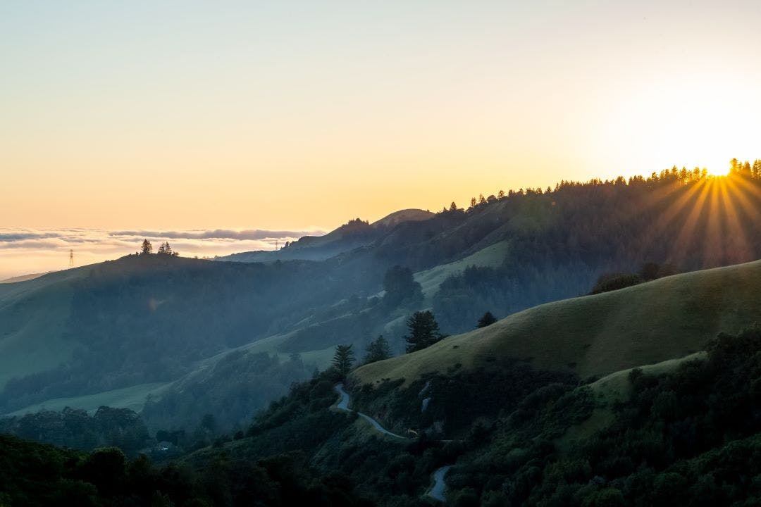 Sunset on Skyline Blvd in Woodside, CA with sun atop the hills and marine layer covering the coast Best Motorcycle Rides in Northern California - Bay Area to the Redwoods