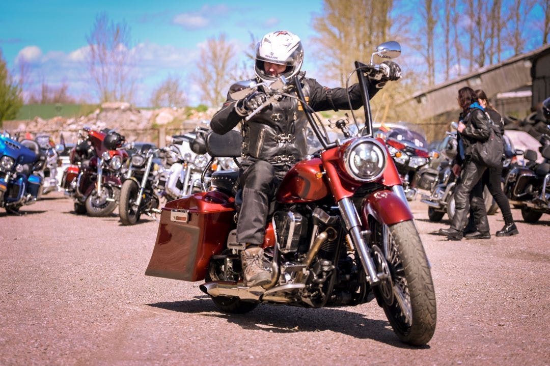 Man on a motorcycle in the street near a group during a biker show Your Guide to Upcoming Fall Motorcycle Rallies & Events - Plan Your Trip Now