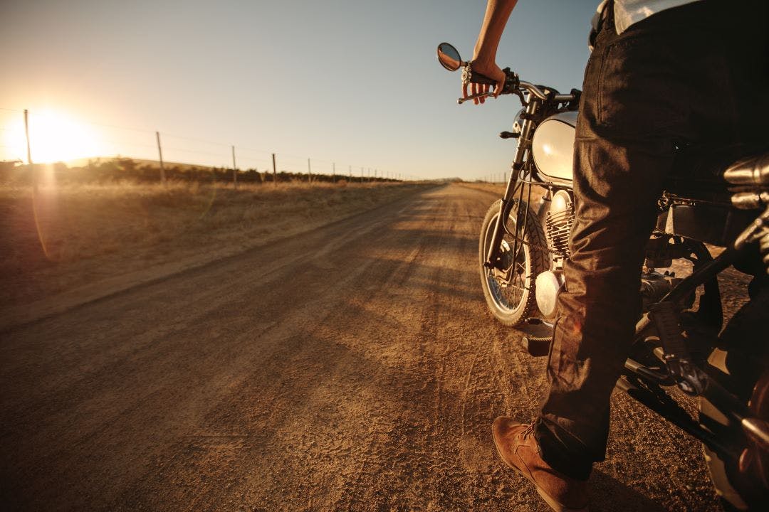 Rider standing on rural road with his bike Best Motorcycles for Short(er) Riders (<5'7" - ish)