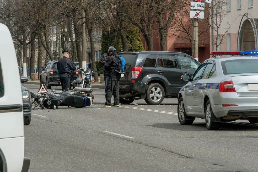 Accident in the city a broken motorcycle and a car. Registration of a traffic accident. Traffic jam due to an accident, police car, police, people Motorcycle Rental Insurance: How Does It Work?