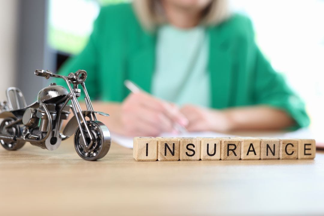 Motorcycle model and word insurance on table, blurred manager with documents in background Motorcycle Rental Insurance: How Does It Work?