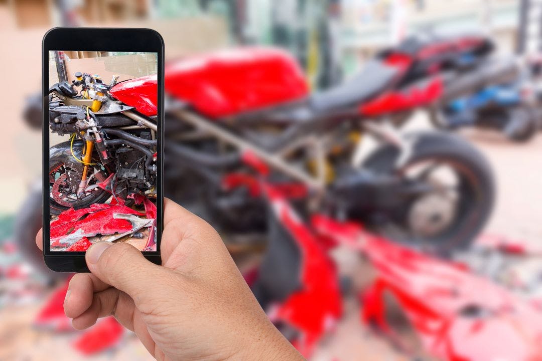 Close up hand holding smartphone and take photo of motorbike accident Here's What to Do After a Motorcycle Accident on a Rental