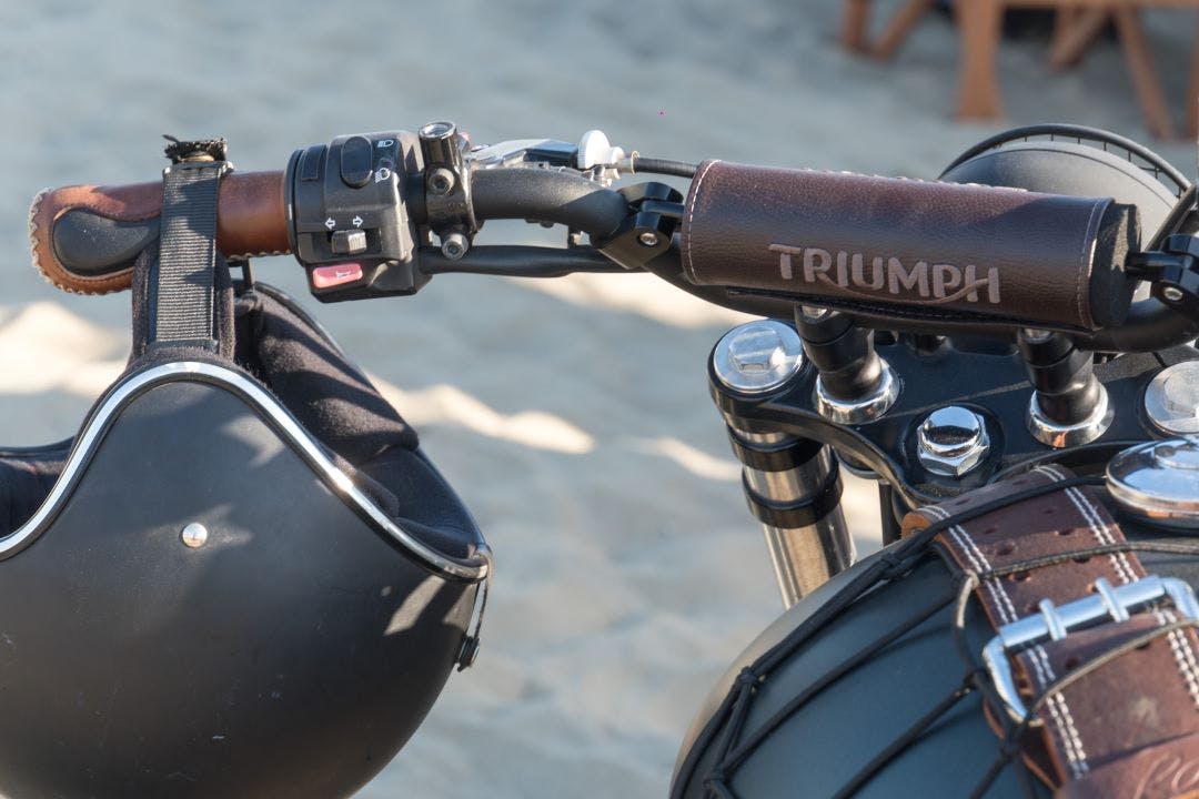 feature close up of old triumph motorcycle handlbar with helmet Best Triumph Motorcycles of All Time (And Today)