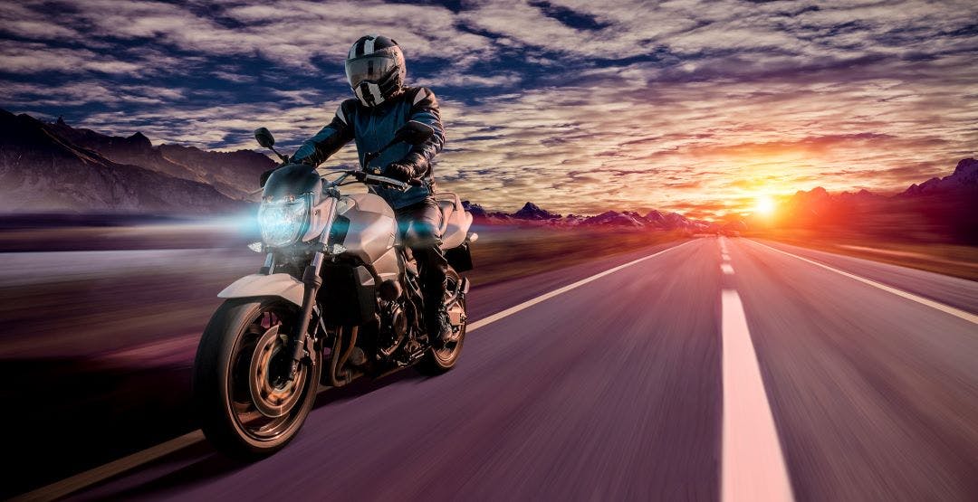 motorcyclist rides home in the evening on a highway while sunset How Does Mileage Affect the Value of a Motorcycle?