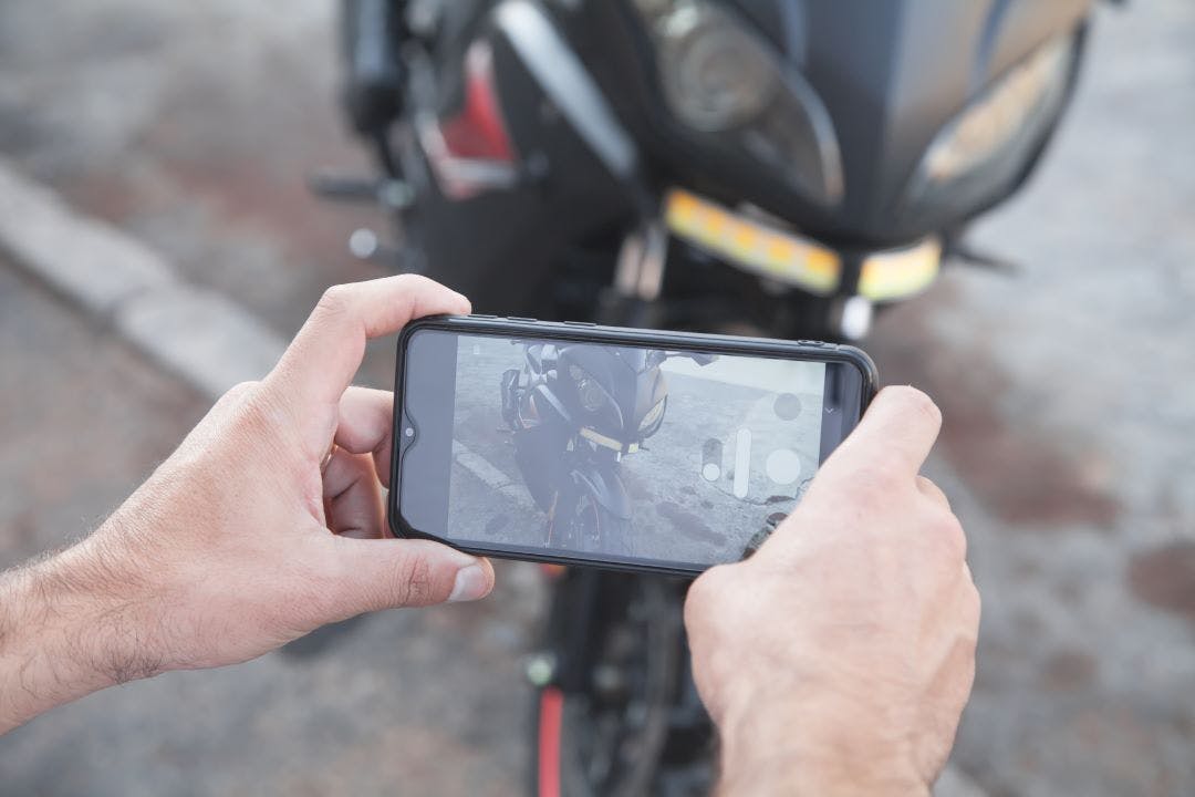 Man taking photo of a motorcycle on his phone How to Market Your Motorcycle for Sale or Rent