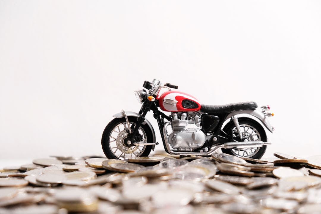 Modern classic motorcycle model on many of coins background, Finance concept How to Market Your Motorcycle for Sale or Rent