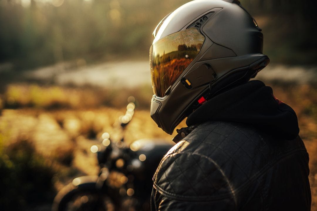 biker with helmet and leather jacket with his bike in the background Motorcycle Helmets Frequently Asked Questions