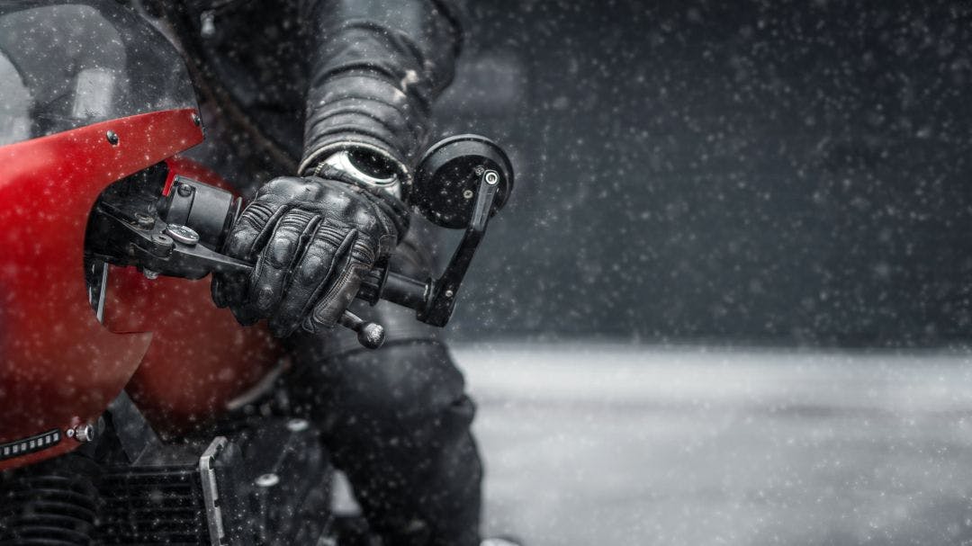 Hand in glove on motorcycle handlebar in winter Riding Gear by Season: What You Should Wear & When