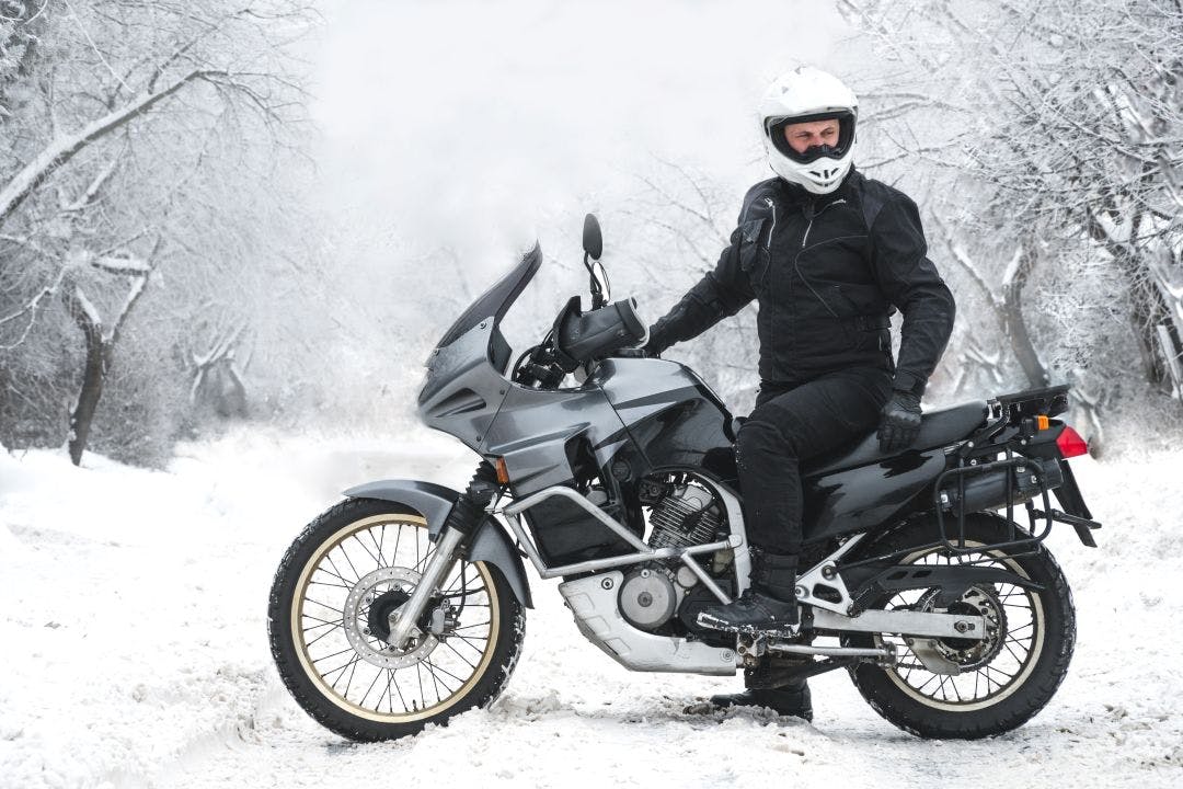 Rider man on adventure motorcycle. Winter fun. snowy day. the snow under the wheels of a motorbike. Enduro. off road dual sport travel tour, active life style concept. winter clothes, equipment Riding Gear by Season: What You Should Wear & When