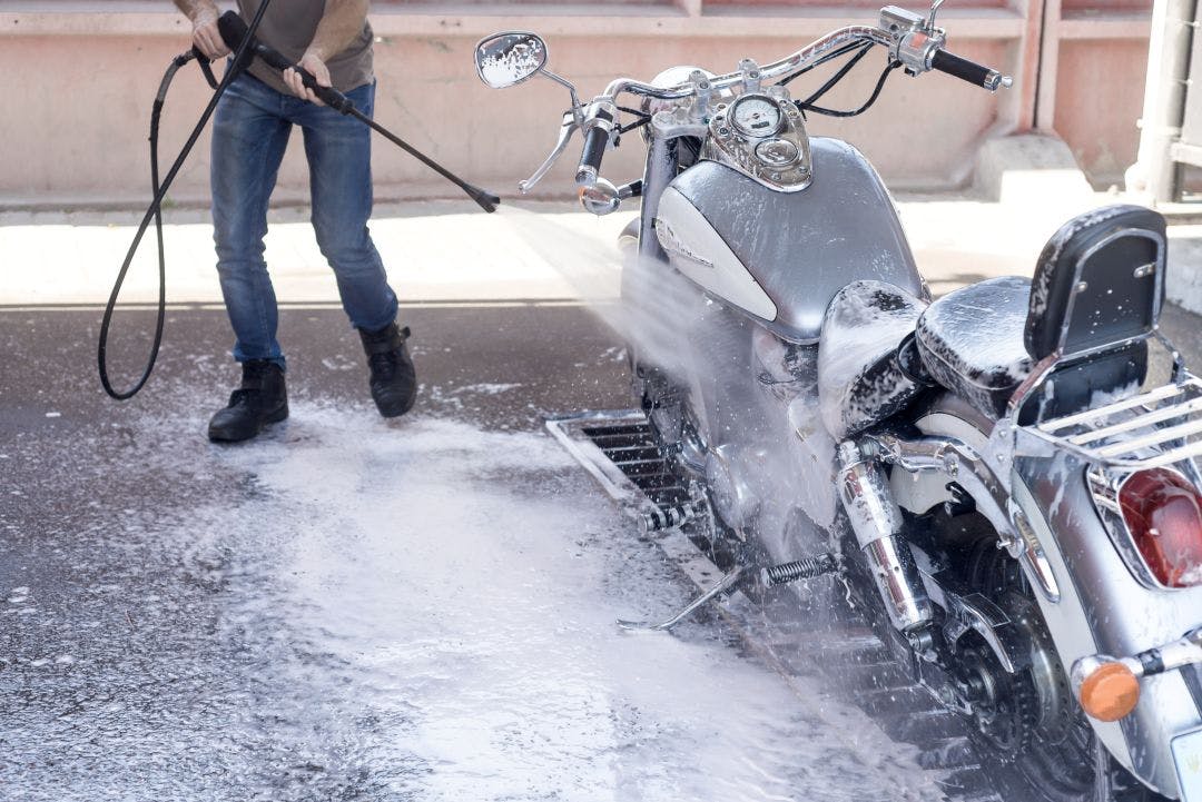 Man washes a motorbike at the car wash by water Tips for How to Store Your Motorcycle for Winter