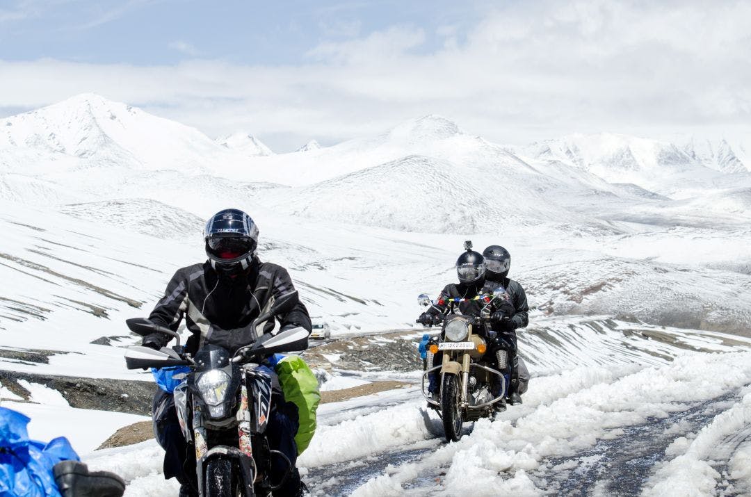 motorcycle riders riding through slush snow covered roads in the mountain How to Stay Warm on a Motorcycle