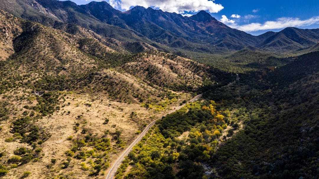 Aerial panorama of Madera Canyon in the Santa Rita Mountains, Arizona in the Fall with purple mountains, green, yellow, orange trees and bushes, blue Best Motorcycle Rides in Tucson, Arizona