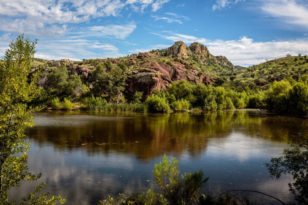 Red cliffs reflected in the peaceful waters of Peña Blanca Lake in the Tumacacori Highlands of Southern Arizona Best Motorcycle Rides in Tucson, Arizona