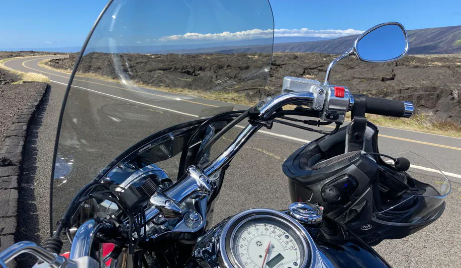 Foto de una motocicleta al costado de un camino desierto en Hawái con una hermosa vista abierta por millas