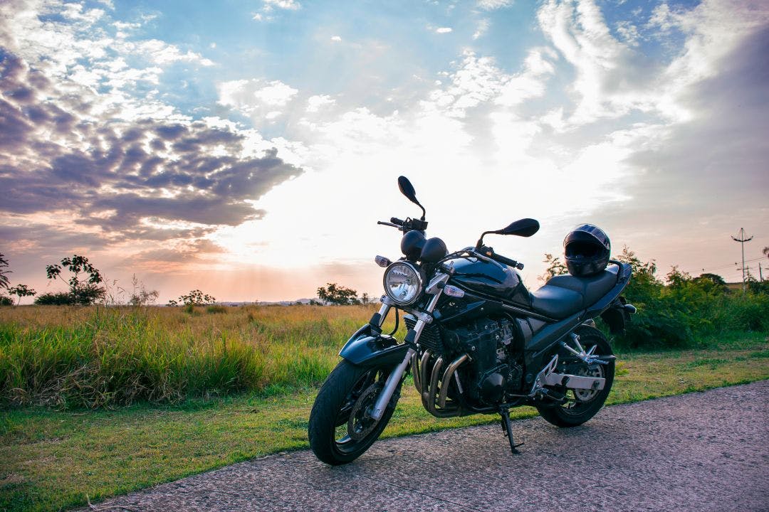 A black motorcycle helmet placed on the seat of a black motorcycle parked on the street with a natural landscape How Can I Find Out What My Motorcycle Is Worth?