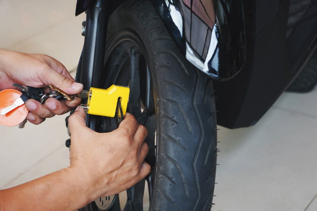 Motorcycle owner use a disc brake lock on a motorbike .Motorcycle Security and Anti-Theft Systems Motorcycle Travel: Keeping Your Bike Locked & Safe