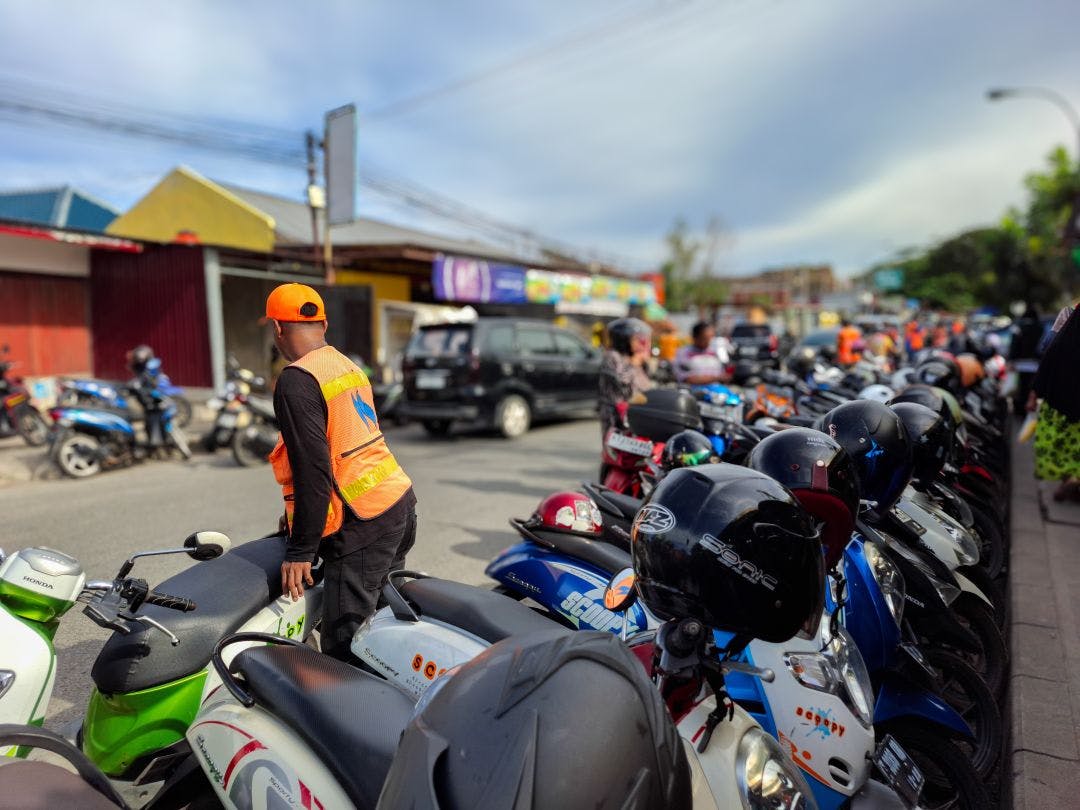 various brands and types of motorbikes are parked and regulated by parking attendants wearing orange vests Your 2025 Summer Motorcycle Travel Guide