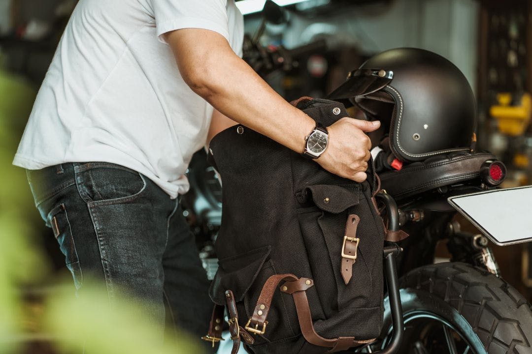 rider install a motorcycle saddlebag or side bag on luggage bracket vintage motorbike motorcycle travel concept Your 2025 Summer Motorcycle Travel Guide