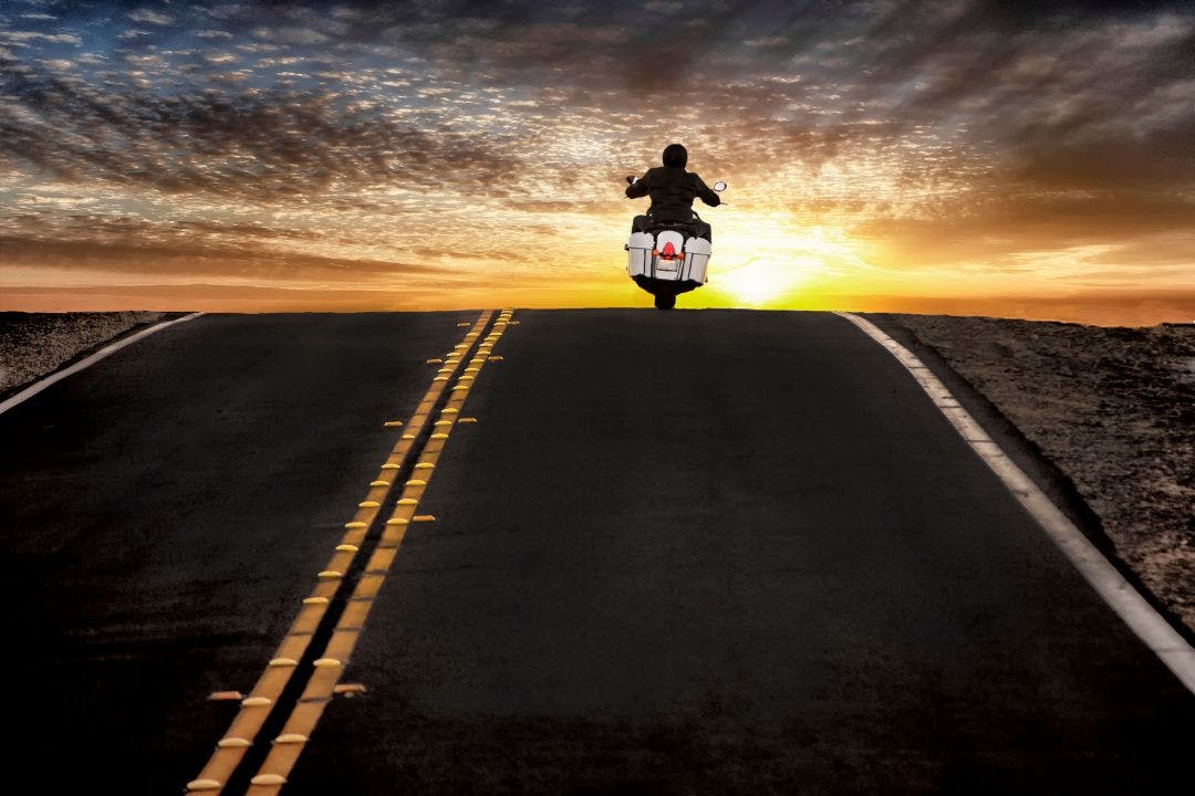Motorcycle rider on street riding toward sunset sky Top Rented Motorcycles in California – Rider Favorites