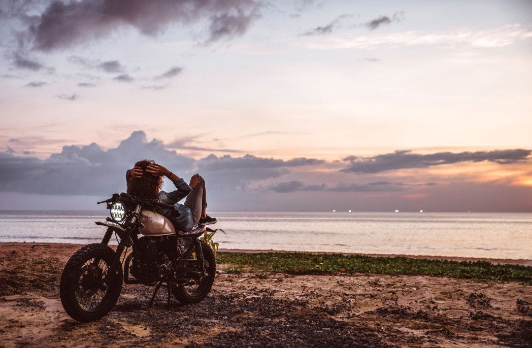 Beautiful girl having fun driving her custom cafe racer motorcycle, enjoying the sunset on the beach Ocean City Bikefest Info & Events - Sept 10-14 2025 - OCMD