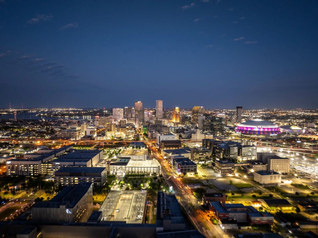 Glowing New Orleans city skyline at dusk with illuminated buildings, busy streets Top 5 Scenic Motorcycle Roads in Louisiana