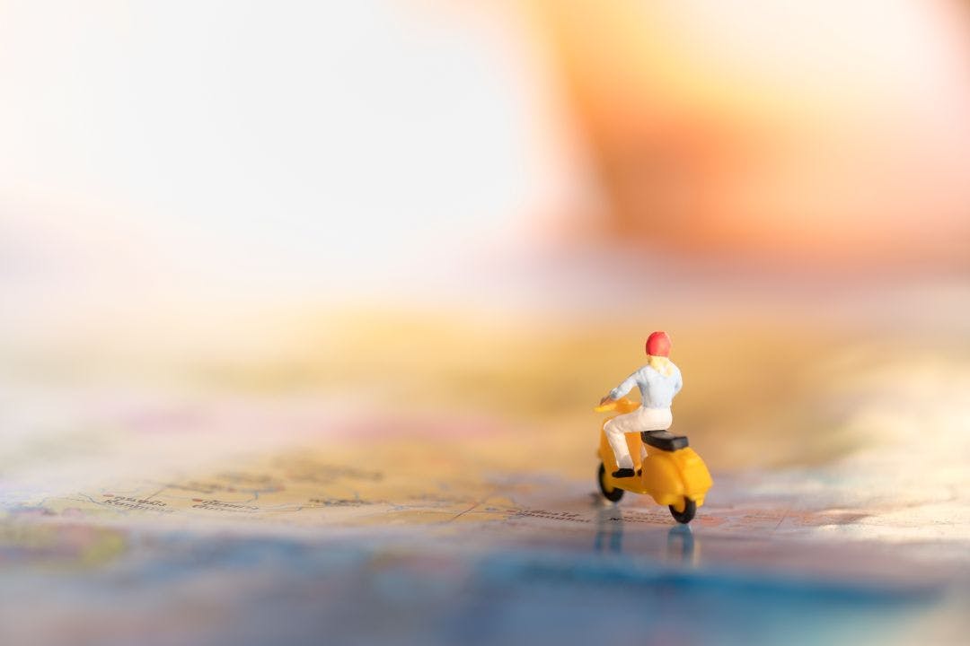 Travel Concept. Woman traveler miniature figures ride motorcycle on a map How to Plan & Prepare for Longer Distance Motorcycle Trips
