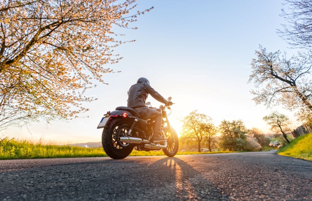 Back view of motorcycle driver on road 5 Late-Summer Motorcycle Getaways to Maximize The Season