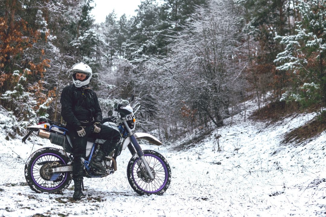 rider on motorcycle in snowy forest dual sport adventure Best Time to Rent a Motorcycle: Seasonal Trends & Pricing