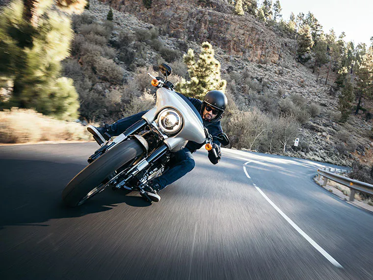 Homem passando numa curva em uma motocicleta Harley-Davidson alugada.