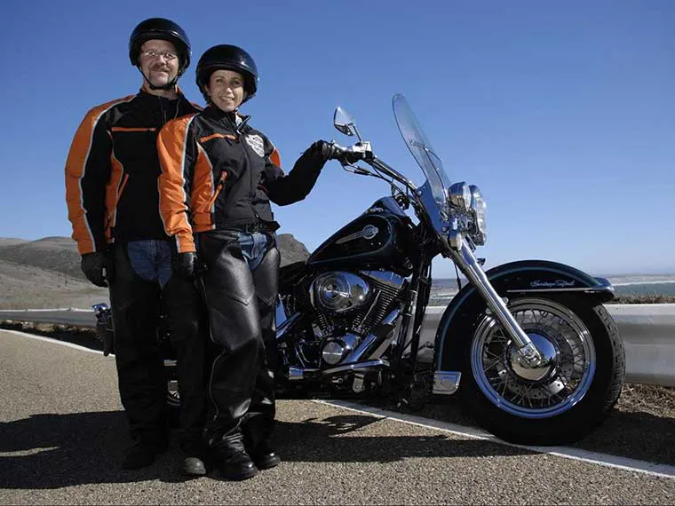 Homem e mulher andando na motocicleta alugada Harley-Davidson.