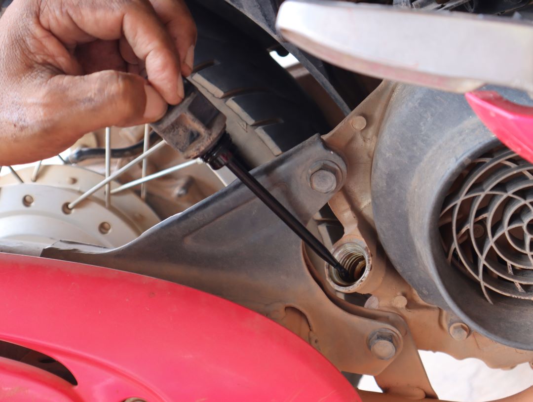 foto em close-up de alguém verificando os níveis de óleo em uma motocicleta, instruções DIY sobre como trocar o óleo da motocicleta