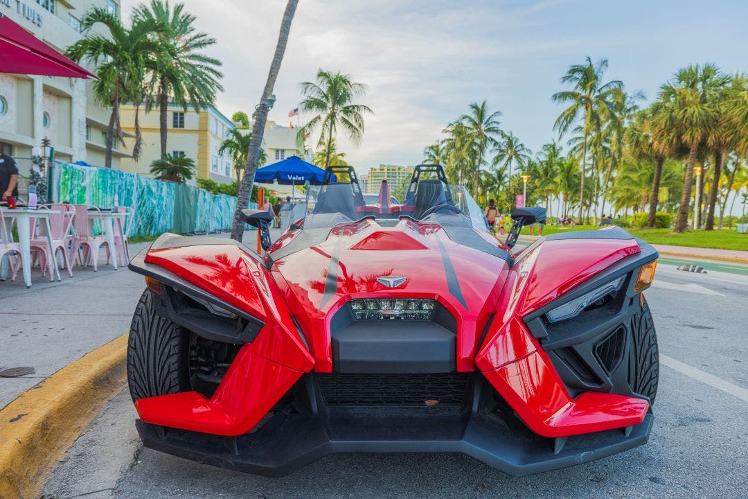 picture of a red Polaris slingshot parked on Ocean Drive in Miami Florida slingshot rentals in Florida