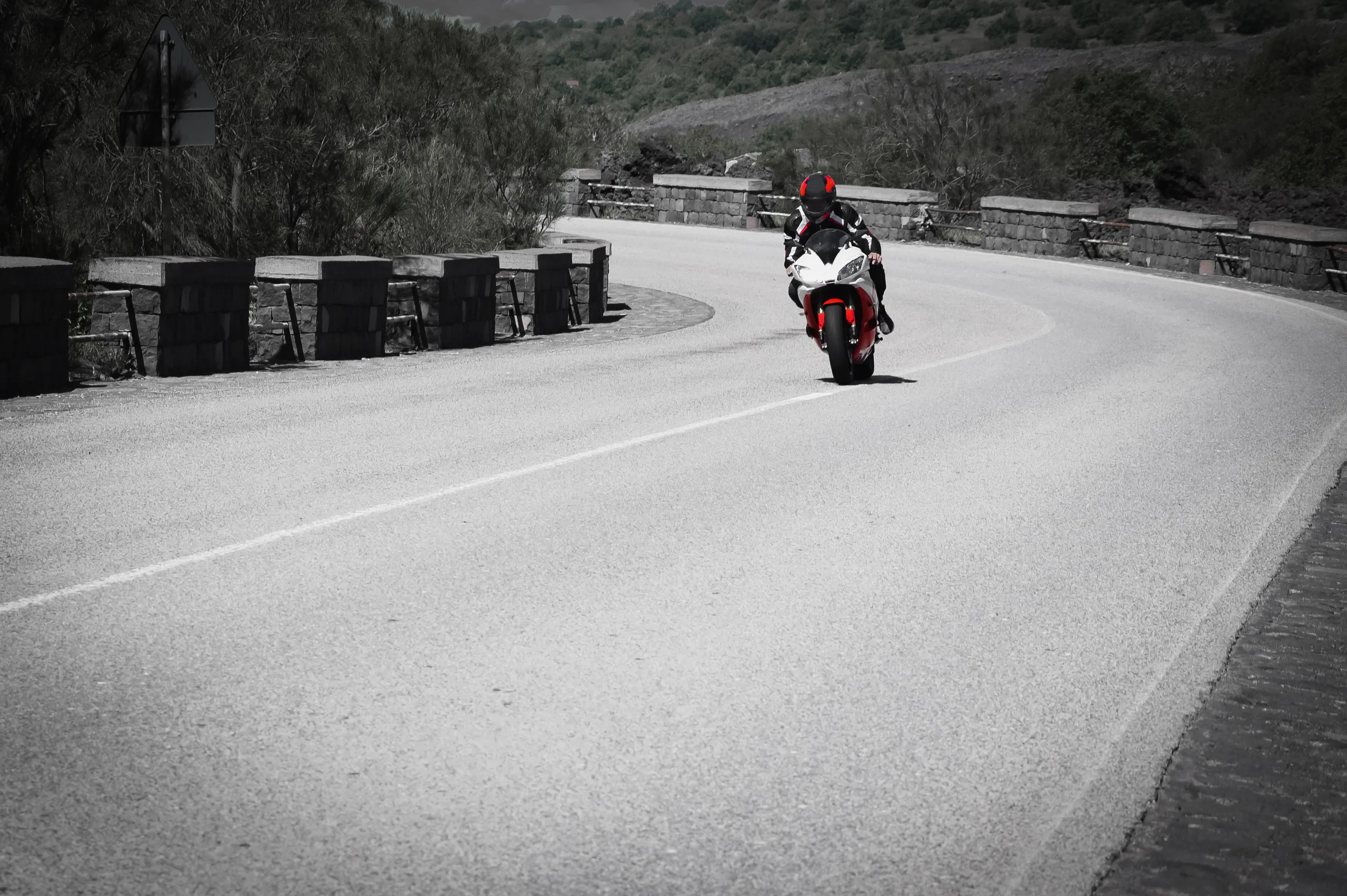 Conductor de motocicleta con casco montando una moto deportiva en un camino sinuoso panorámico
