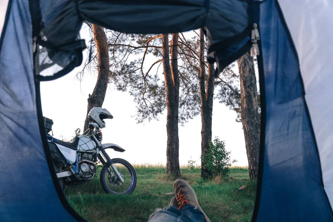 Vista externa de dentro de uma barraca. Acampamento na floresta, turismo de motocicleta, enduro de dupla pista, aventura em barraca e off road, conceito de estilo de vida ativo