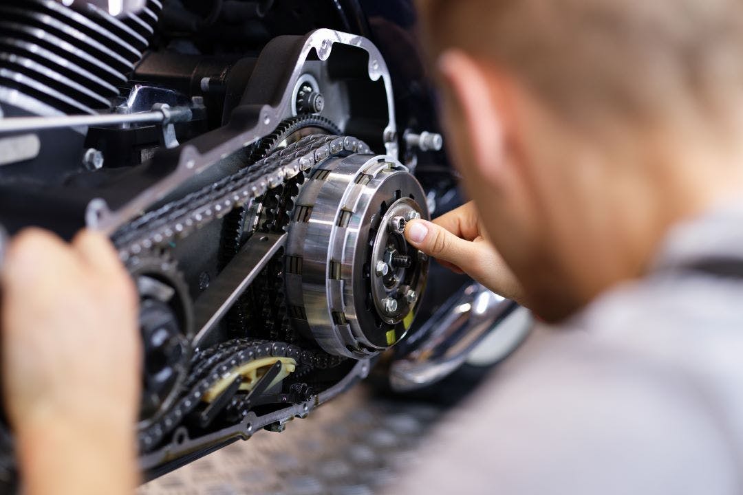 picture of man adjusting chain on his motorcycle as part of a monthly DIY motorcycle maintenance checklist