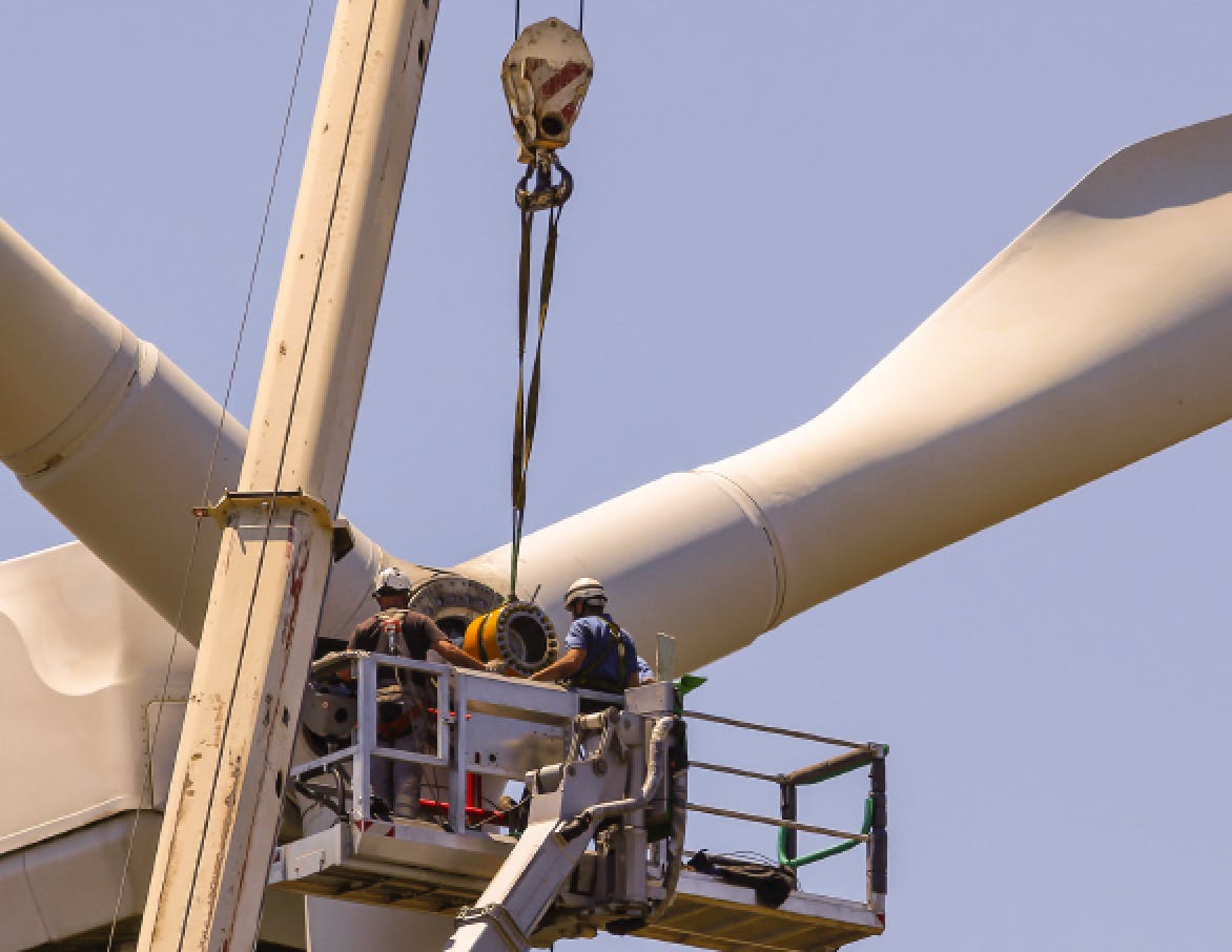 Turbine technicians repairing a windmill.