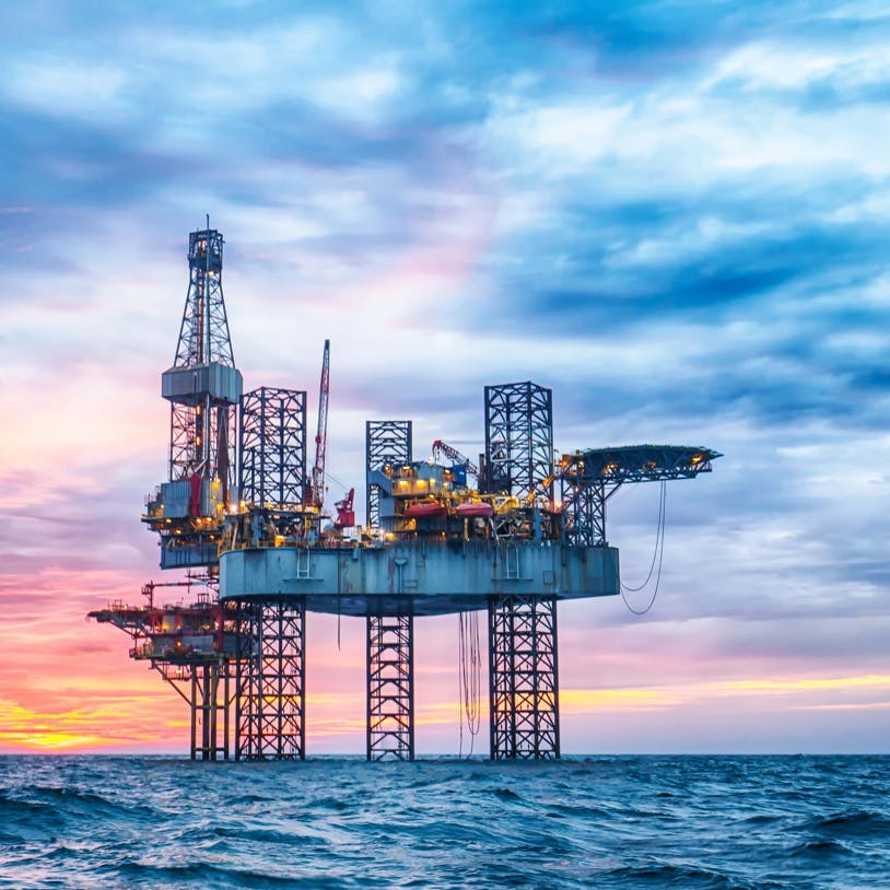 An offshore drilling rig at sunset.