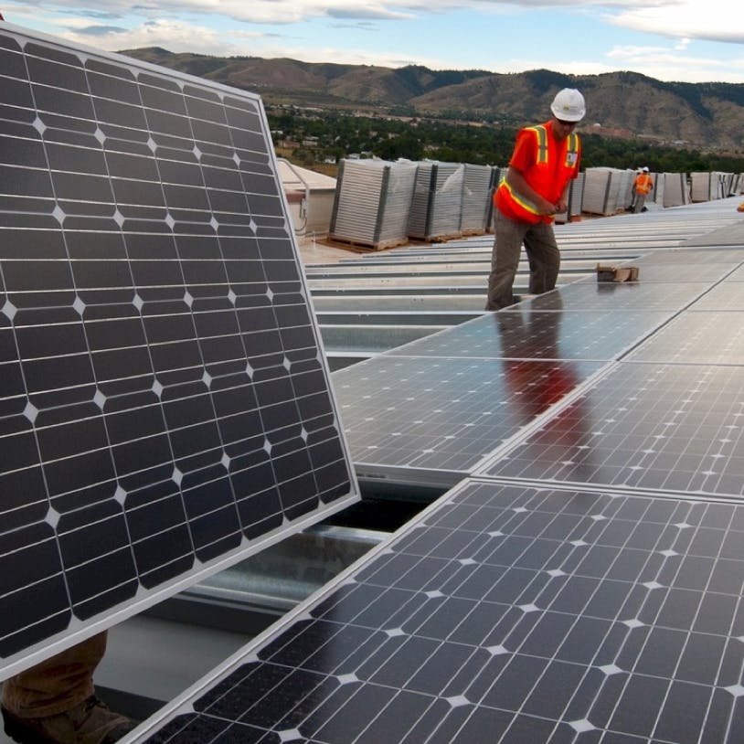 Solar technicians install panels at an industrial solar site.