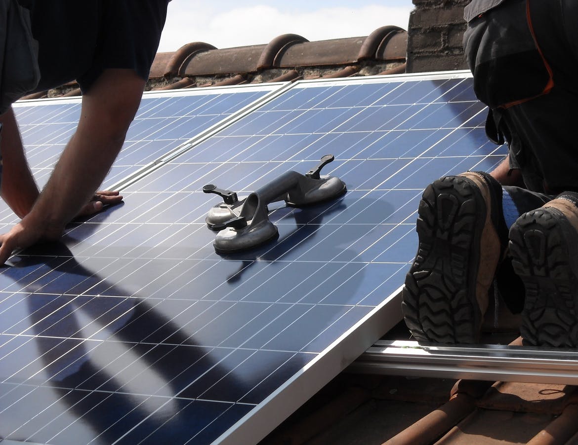 A solar technician installs a solar panel.