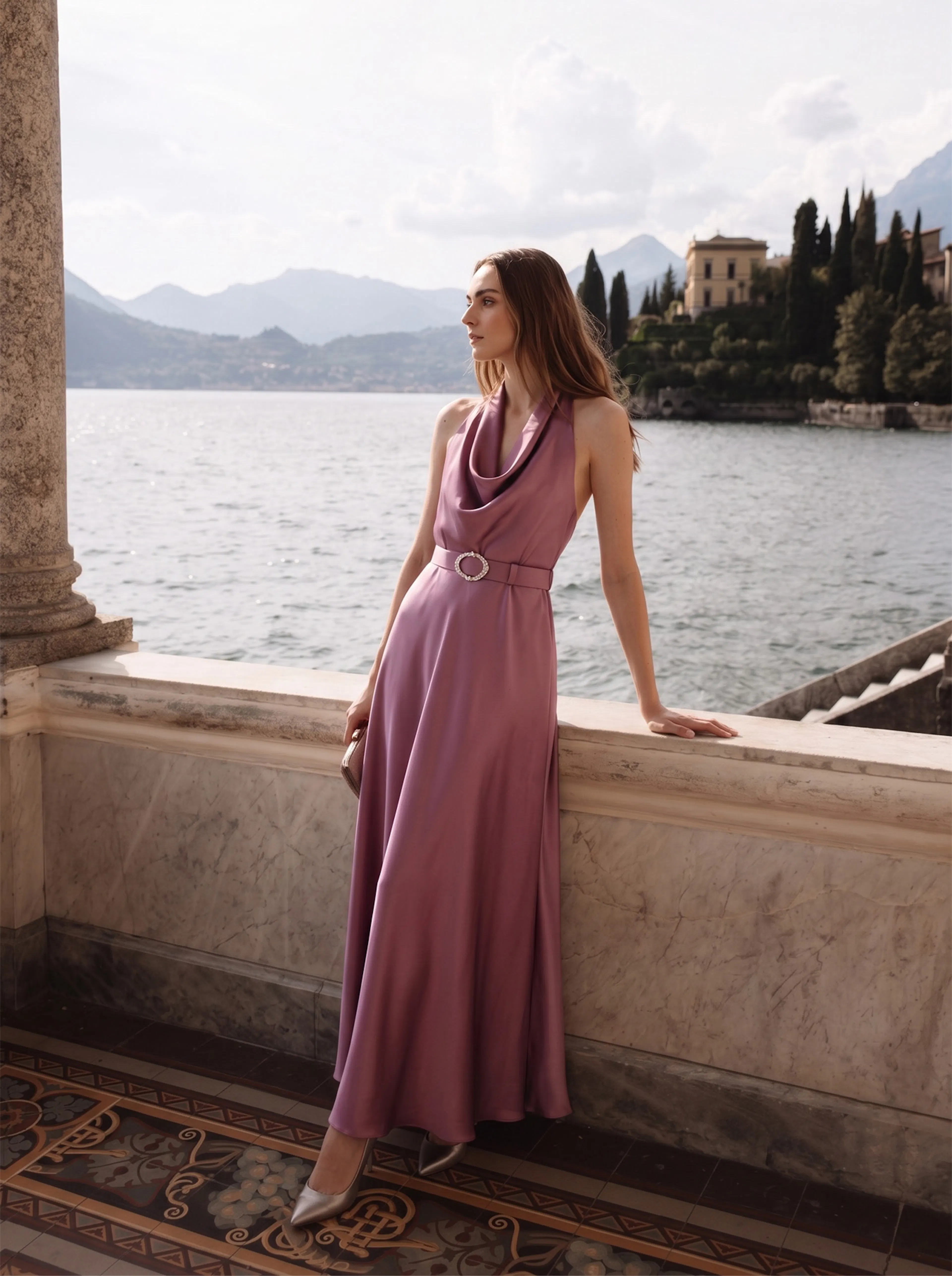 A woman in a flowing lavender dress leans on a marble balustrade by a serene lake, surrounded by mountains and villas. The scene is tranquil and elegant.