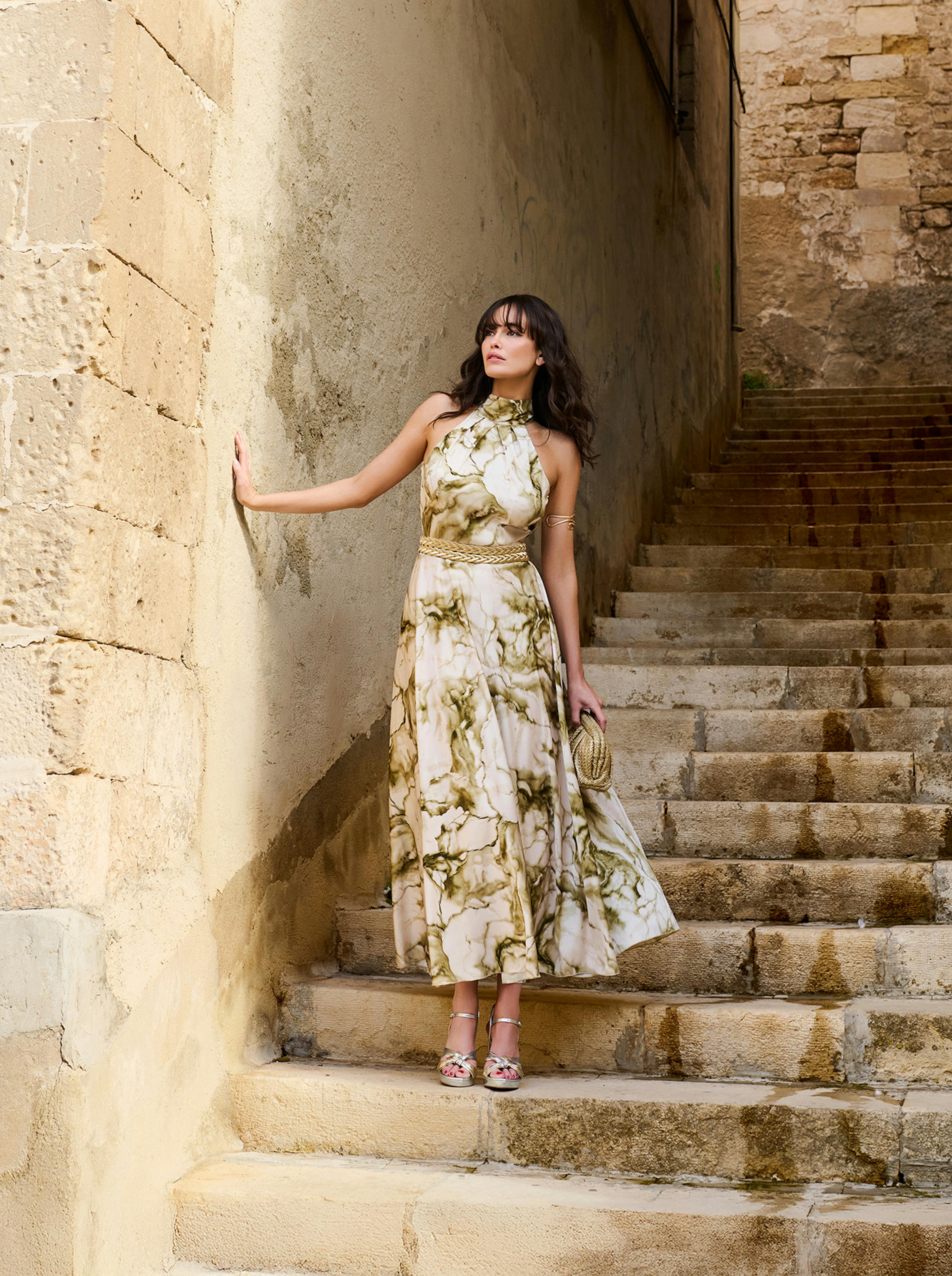 A woman in a stylish dress stands confidently on a staircase